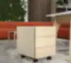 Šviesaus ąžuolo mobilus stalčių blokas su trimis stalčiais ant ratukų moderniame biure su žaliąja siena ir oranžine sofa