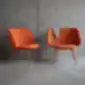 Dvi oranžinės EVY kėdės prie betoninės sienos